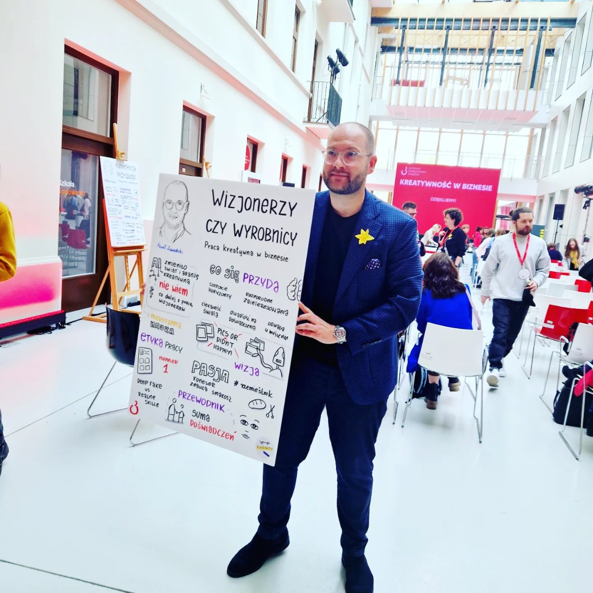 Prelegent pozuje z notatką wizualną ze swojego wystąpienia, konferencja Kreatywność w biznesie w CKT Targowa
